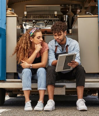 A man showing some data to her co-worker on an HP laptop in tablet mode.